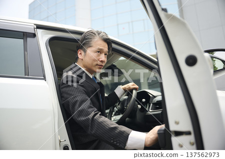 A male businessman in his 50s getting into a car A male businessman in his 50s getting into a car 137562973