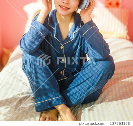 A woman in pajamas listening to music in bed: Happy Pop A woman in pajamas listening to music in bed: Happy Pop 137563338