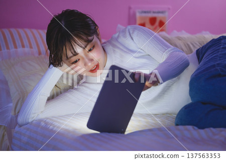 Woman looking at tablet in bed: Happy Pop 137563353