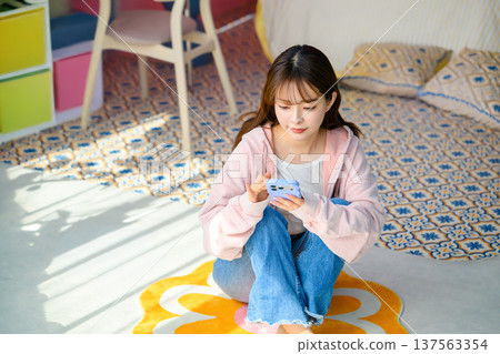 Woman sitting on the floor looking at her smartphone: Happy Pop Woman sitting on the floor looking at her smartphone: Happy Pop 137563354