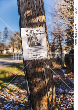 Missing woman reward poster attached to wooden utility pole along suburban street in USA 137563509