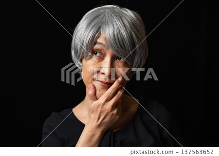 一位頭髮花白的老婦人，手托著下巴，咧嘴笑著。 137563652