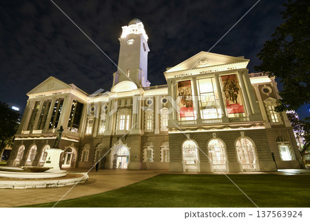 Night view of the oldest Victoria Theatre and Concert Hall in Empress Place, Singapore, with a complex of two buildings and a clock tower. Night view of the oldest Victoria Theatre and Concert Hall in Empress Place, Singapore, with a complex of two buildings and a clock tower. 137563924