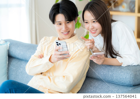 Young couple looking at a smartphone in the living room Young couple looking at a smartphone in the living room 137564041