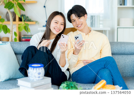 年輕夫婦在客廳裡看智能手機 137564050