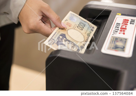 A woman who puts money into an automated teller machine A woman who puts money into an automated teller machine 137564084