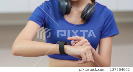 Tech-Savvy Fitness. Young woman checking smartwatch during workout. Tech-Savvy Fitness. Young woman checking smartwatch during workout. 137564602