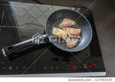 Fish fillet frying in pan on kitchen stove Fish fillet frying in pan on kitchen stove 137565035