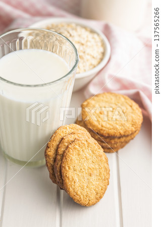 Cookies stacked next to a glass of milk on a wooden table in a bright kitchen setting during daytime Cookies stacked next to a glass of milk on a wooden table in a bright kitchen setting during daytime 137565266