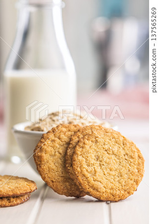 Cookies stacked next to a glass of milk on a wooden table in a bright kitchen setting during daytime Cookies stacked next to a glass of milk on a wooden table in a bright kitchen setting during daytime 137565269
