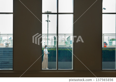 solo asian woman wear protective mask during outdoor break and relax at rooftop with city background solo asian woman wear protective mask during outdoor break and relax at rooftop with city background 137565856