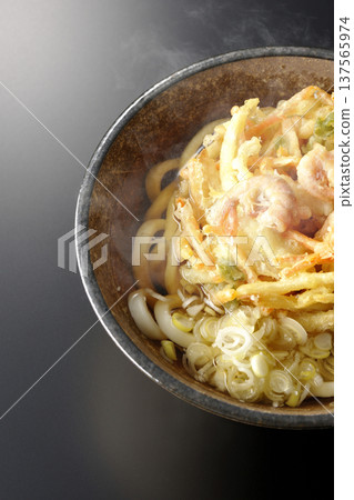 Hot shrimp and vegetable tempura udon noodles photographed against a black background 137565974