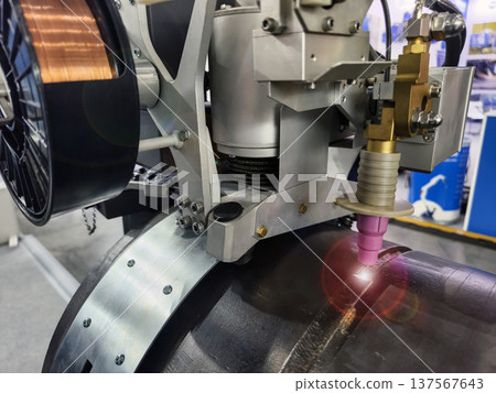 Welding machine performs task on metal surface at industrial facility in workshop setting during daytime Welding machine performs task on metal surface at industrial facility in workshop setting during daytime 137567643