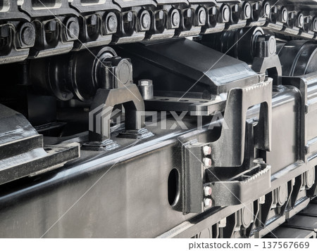 Close view of a tracked vehicle showing its undercarriage and suspension parts in a machinery workshop during daylight 137567669