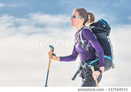 Female ski mountaineer hiking with touring skis in alpine mountains 137569531