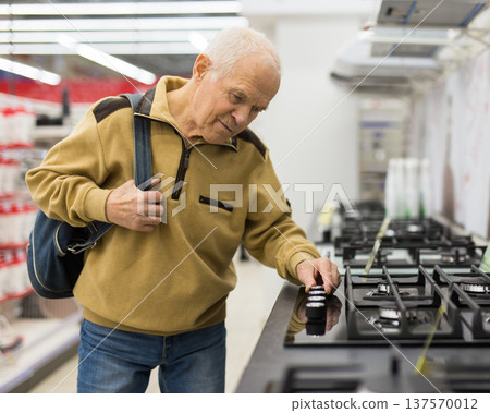 elderly man choosing gas stove in showroom of electrical appliance store elderly man choosing gas stove in showroom of electrical appliance store 137570012