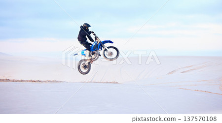 Desert, jump or person driving motorcycle for action, adventure or fitness with performance or adrenaline. Sand, risk or sports athlete on motorbike on dunes for training, exercise or race challenge 137570108