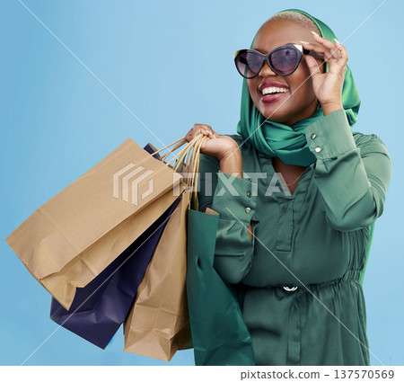 Shopping, sunglasses and black woman with bags, retail and luxury items on a blue studio background. African person, customer and model with expensive clothes, client and boutique products with sales Shopping, sunglasses and black woman with bags, retail and luxury items on a blue studio background. African person, customer and model with expensive clothes, client and boutique products with sales 137570569