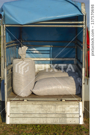 White Sacks Loaded in Small Trailer with Blue Tarp 137570698