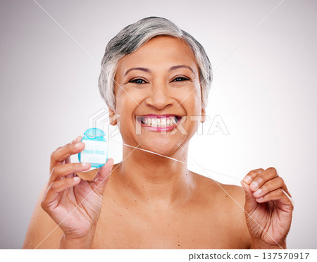 Mature woman, floss and studio portrait for transformation, beauty and healthy mouth by white background. Senior female model, teeth whitening and thread for dental self care, cleaning and change Mature woman, floss and studio portrait for transformation, beauty and healthy mouth by white background. Senior female model, teeth whitening and thread for dental self care, cleaning and change 137570917