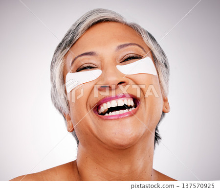 Mature, happy woman and face with eye patches in skincare, cosmetics or anti aging against a studio background. Senior female person or model smile with pads on eyes for facial treatment or routine Mature, happy woman and face with eye patches in skincare, cosmetics or anti aging against a studio background. Senior female person or model smile with pads on eyes for facial treatment or routine 137570925