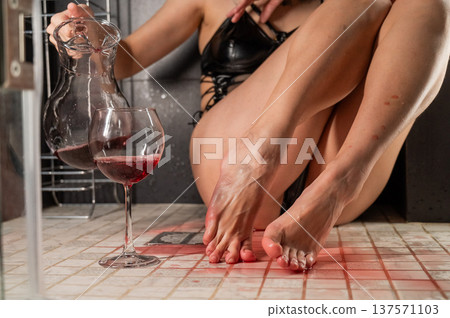 Foot fetish. A woman pours wine from a glass onto her feet in the shower. 137571103