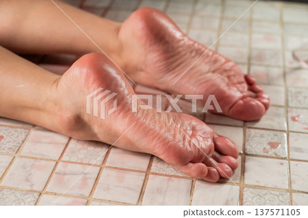Foot fetish. A woman pours wine from a glass onto her feet in the shower. 137571105