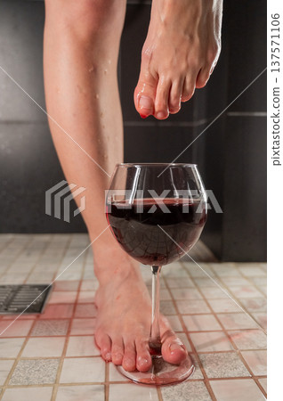 Foot fetish. A woman dips her toes in a glass of red wine. 137571106