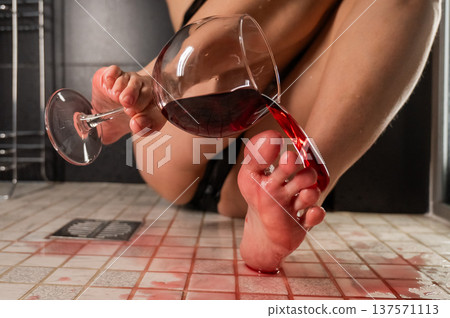 Foot fetish. A woman pours wine from a glass onto her feet in the shower. Foot fetish. A woman pours wine from a glass onto her feet in the shower. 137571113