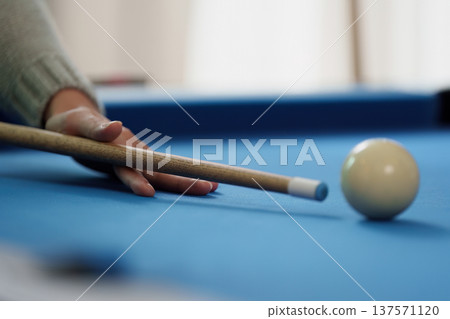 Billiards Game. Close-up of a player preparing to strike the cue ball on a blue pool table. Billiards Game. Close-up of a player preparing to strike the cue ball on a blue pool table. 137571120