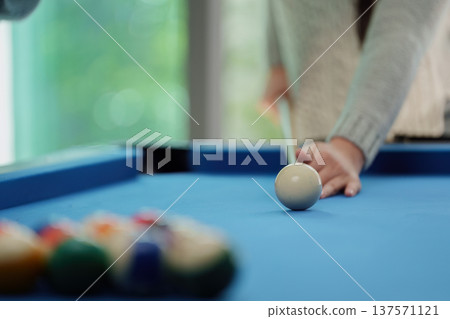 Billiards Action. Player aiming at the cue ball on a blue pool table with colorful balls in the background. 137571121
