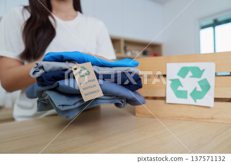 Sustainability. Woman organizing clothes made from recycled materials in eco-friendly lifestyle. 137571132