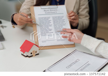 Real Estate Contract Signing. Client discussing terms with agent over contract. Real Estate Contract Signing. Client discussing terms with agent over contract. 137571142