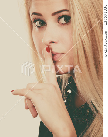 Attractive blonde woman making silence gesture 137571330