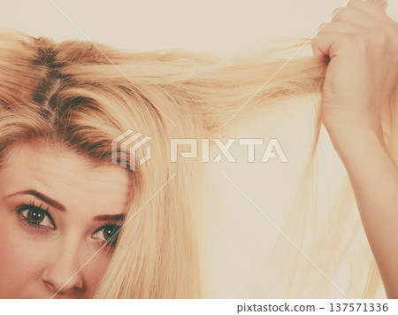 Blonde woman holding her dry hair Blonde woman holding her dry hair 137571336