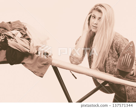 Woman holding iron about to do ironing Woman holding iron about to do ironing 137571344