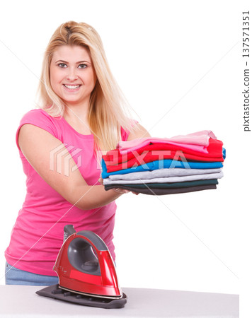 Woman holding folded clothes after ironing 137571351