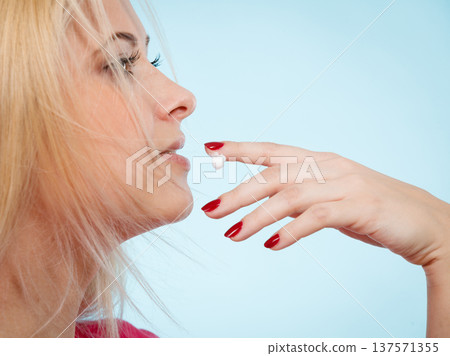 Woman applies lip balm cream to her lips 137571355