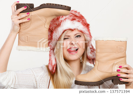 Woman in winter hat holding beige boots. Woman in winter hat holding beige boots. 137571394
