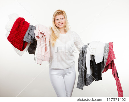 Woman holding big piles of clothing Woman holding big piles of clothing 137571402