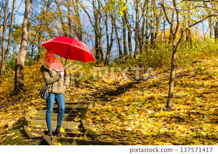 Woman walking in park with umbrella Woman walking in park with umbrella 137571417