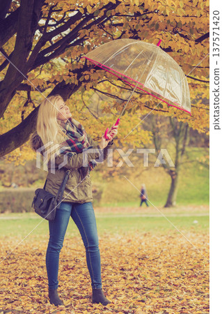 Woman walking in park with umbrella Woman walking in park with umbrella 137571420