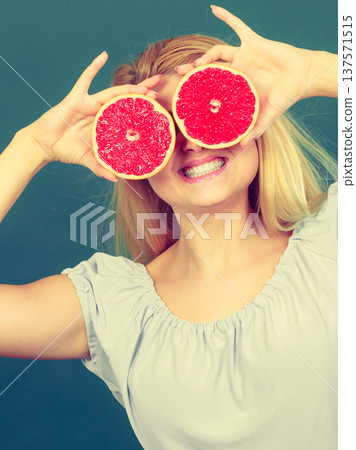 Girl covering her eyes with grapefruits 137571515