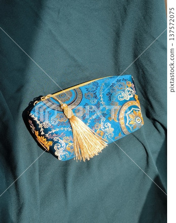 Blue jacquard cosmetic bag on green draped fabric in oriental style Blue jacquard cosmetic bag on green draped fabric in oriental style 137572075