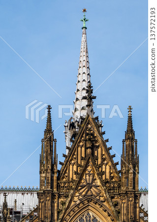 Cologne Cathedral in Germany features intricate Gothic architecture with tall spires and detailed stonework against a blue sky. 137572193