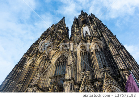 Cologne Cathedral in Germany features intricate Gothic architecture with tall spires and detailed stonework against a blue sky. Cologne Cathedral in Germany features intricate Gothic architecture with tall spires and detailed stonework against a blue sky. 137572198