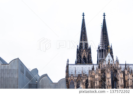 Cologne Cathedral in Germany features intricate Gothic architecture with tall spires and detailed stonework against a blue sky. 137572202