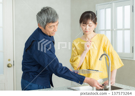 A man in work clothes explaining about plumbing A man in work clothes explaining about plumbing 137573264