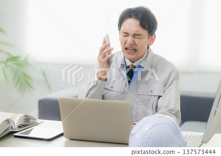 A man in work clothes dealing with complaints at work 137573444