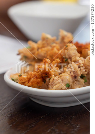 Crispy fried squid tentacles served on a plate with a lemon wedge in a restaurant setting, a golden seafood appetizer with crunchy texture and savory flavor. 137574230